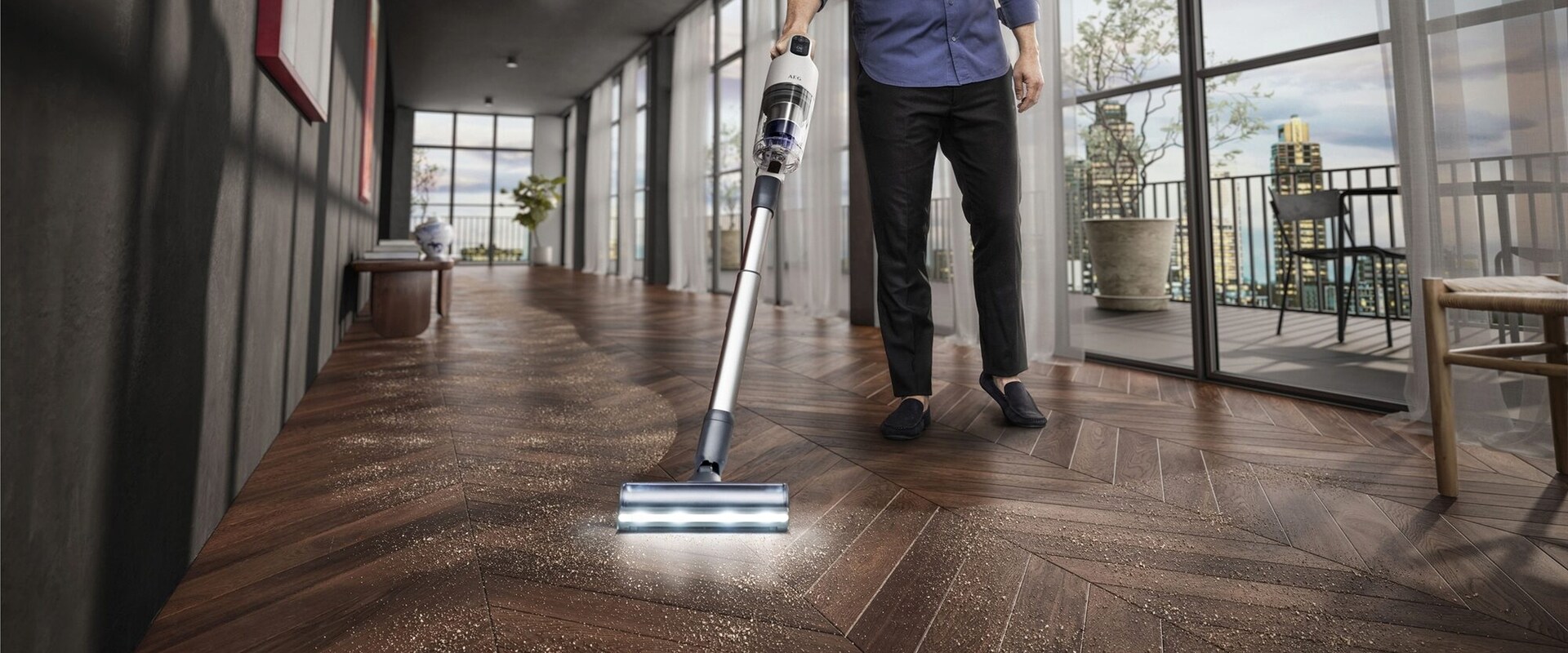 Un homme passe l'aspirateur balai AEG sur un parquet.